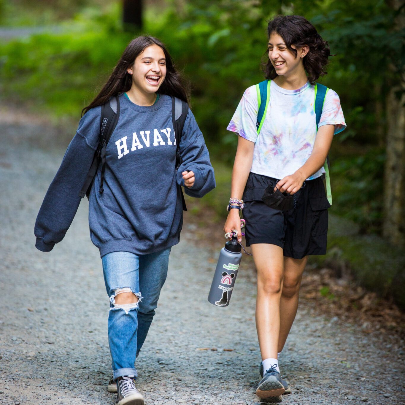 Two smiling campers naturally walking on a trail at camp
